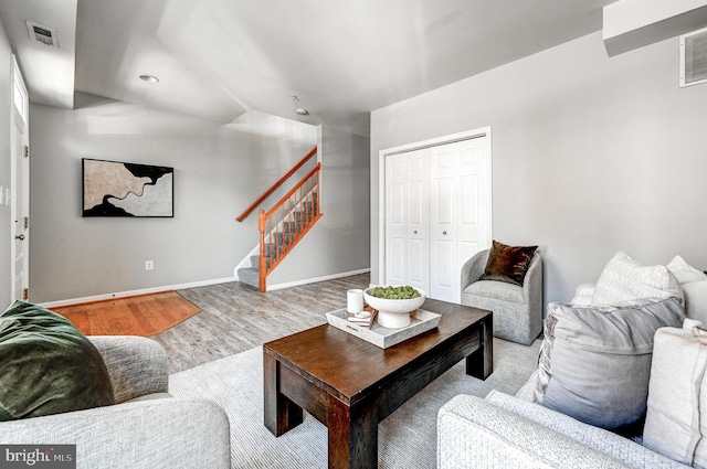 living room with visible vents, wood finished floors, baseboards, lofted ceiling, and stairs