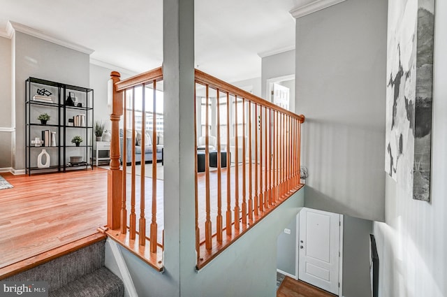 stairway with wood finished floors, baseboards, and ornamental molding