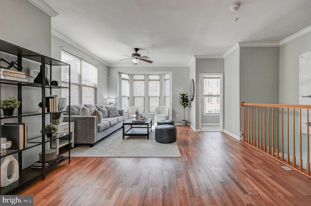 living area with ceiling fan, baseboards, wood finished floors, and crown molding