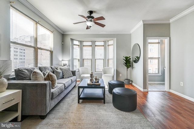 living room with wood finished floors, a ceiling fan, baseboards, and ornamental molding