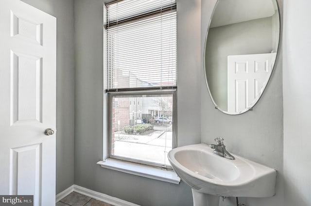 bathroom featuring tile patterned flooring, baseboards, and a sink