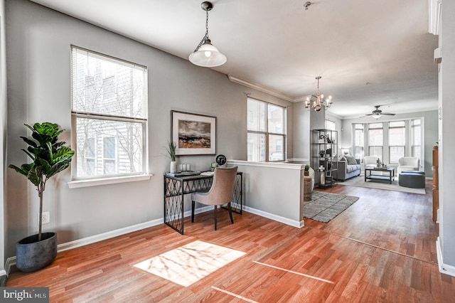 interior space featuring baseboards, pendant lighting, and light wood finished floors