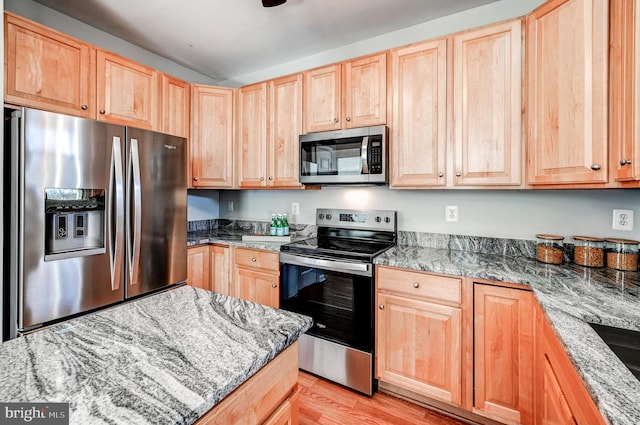 kitchen featuring light stone counters, appliances with stainless steel finishes, light wood-style flooring, and light brown cabinetry