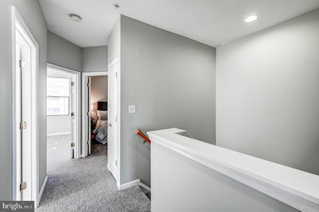 hall featuring baseboards, carpet floors, and an upstairs landing