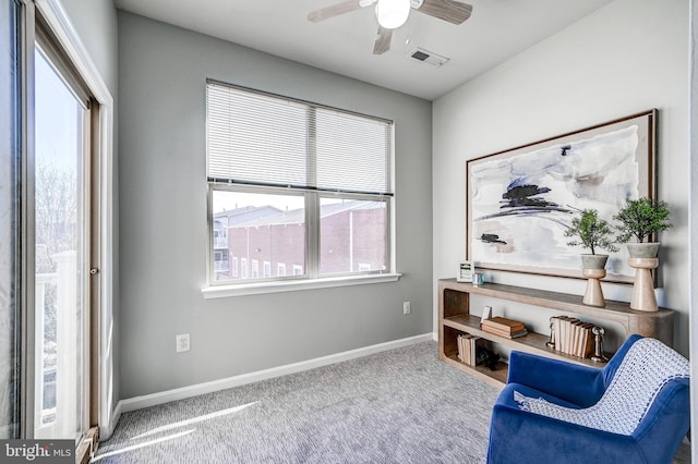 living area featuring visible vents, plenty of natural light, baseboards, and carpet