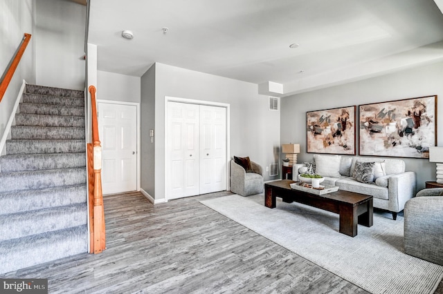 living area featuring stairs, wood finished floors, visible vents, and baseboards