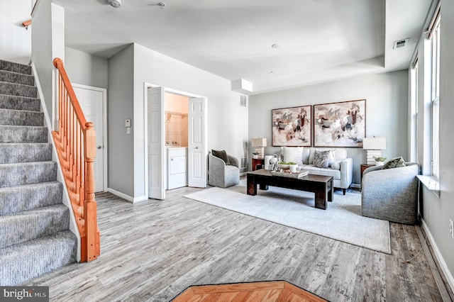 living area featuring stairs, wood finished floors, visible vents, and independent washer and dryer