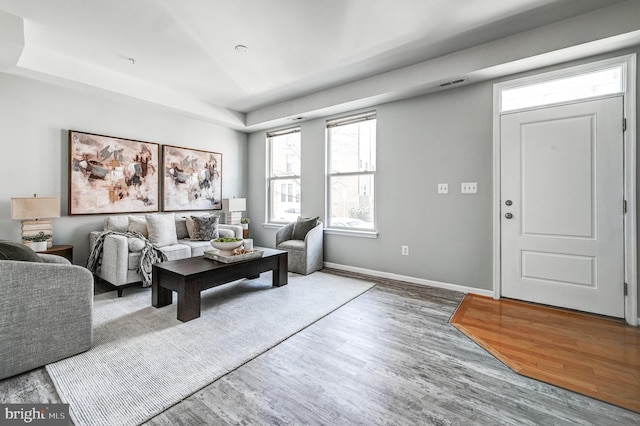 living area with visible vents, wood finished floors, and baseboards