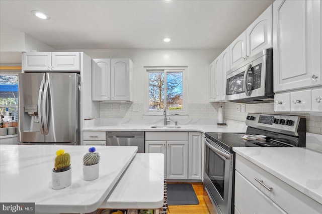 kitchen with a sink, stainless steel appliances, and tasteful backsplash