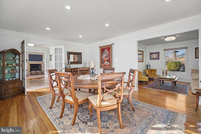 dining area with recessed lighting, light wood-style flooring, a fireplace, and ornamental molding