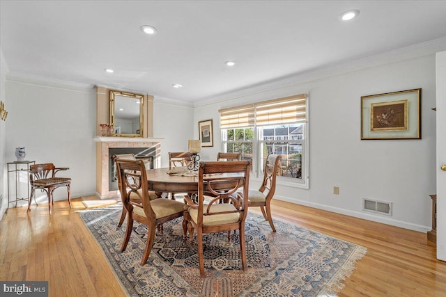 dining area featuring visible vents, ornamental molding, and light wood-style flooring