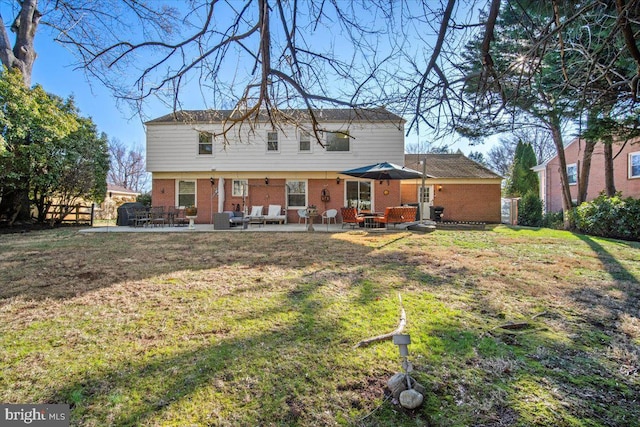 rear view of property with a patio area, a yard, and brick siding