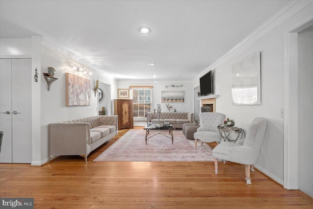 living area featuring ornamental molding, a fireplace, and hardwood / wood-style flooring