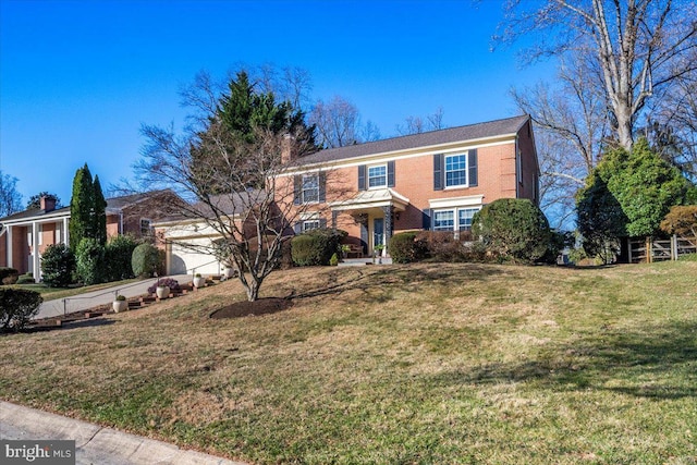 view of front of home featuring brick siding, an attached garage, a chimney, and a front yard