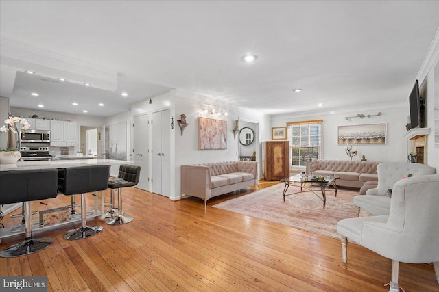 living area featuring recessed lighting, crown molding, and light wood finished floors