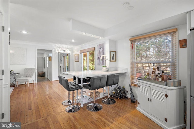 dining space featuring light wood-style flooring, baseboards, and ornamental molding