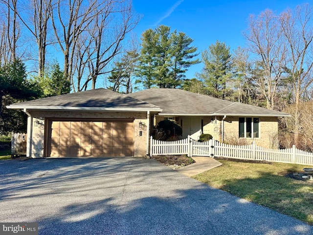 ranch-style house featuring an attached garage, driveway, and a fenced front yard