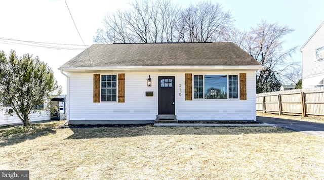 bungalow-style home with entry steps, fence, and roof with shingles