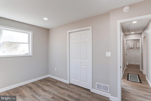 unfurnished bedroom featuring visible vents, attic access, and wood finished floors