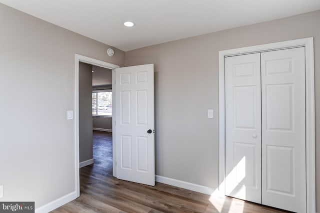 unfurnished bedroom featuring a closet, recessed lighting, baseboards, and wood finished floors