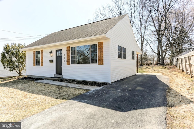 view of front of home with a shingled roof and fence