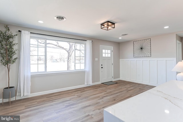 foyer entrance with a wainscoted wall, recessed lighting, light wood-style floors, and visible vents