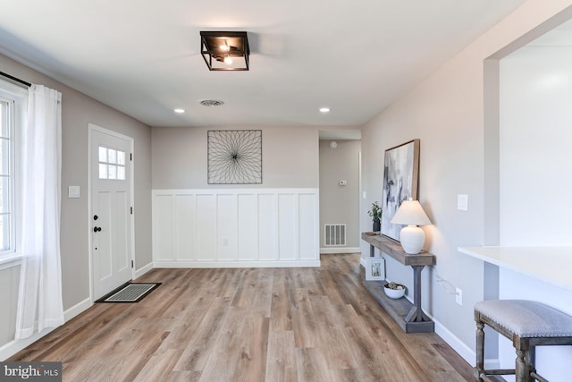 entrance foyer featuring recessed lighting, visible vents, wainscoting, and light wood-style floors