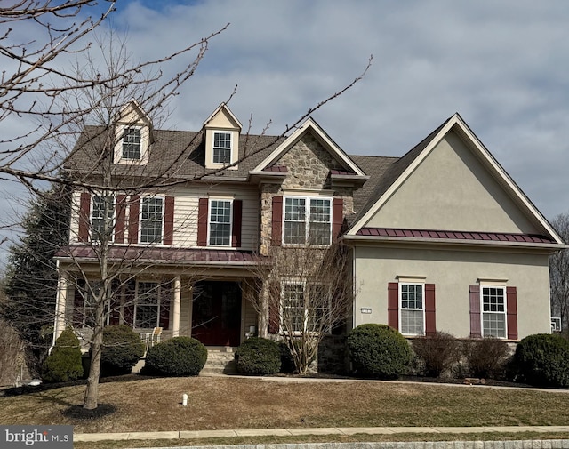 view of front of property featuring a standing seam roof, metal roof, stone siding, and stucco siding