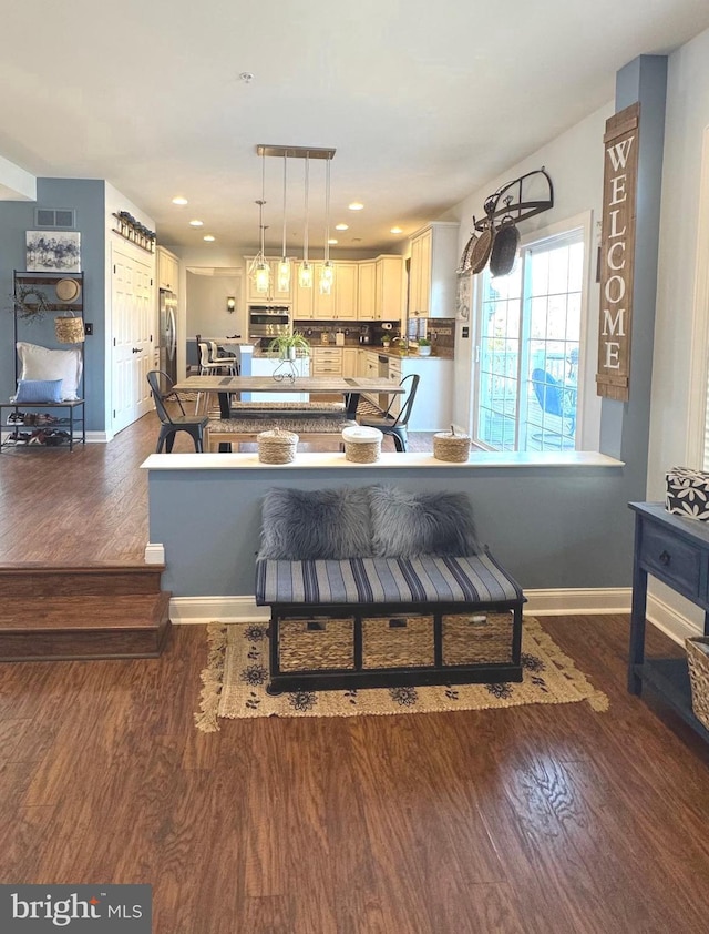 kitchen with wood finished floors, baseboards, stainless steel appliances, decorative light fixtures, and tasteful backsplash