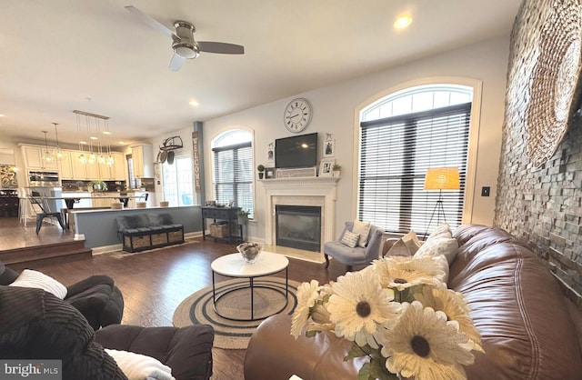 living area featuring a glass covered fireplace, recessed lighting, ceiling fan, and dark wood-style flooring