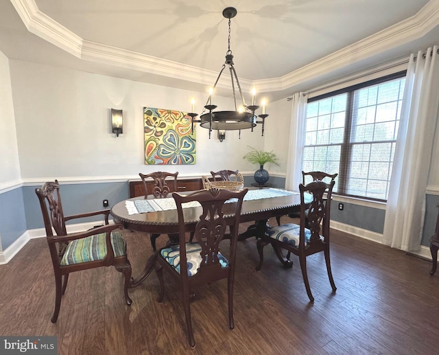 dining room with ornamental molding, a raised ceiling, baseboards, and wood finished floors