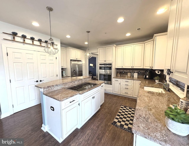 kitchen featuring a sink, light stone counters, dark wood finished floors, a center island, and stainless steel appliances