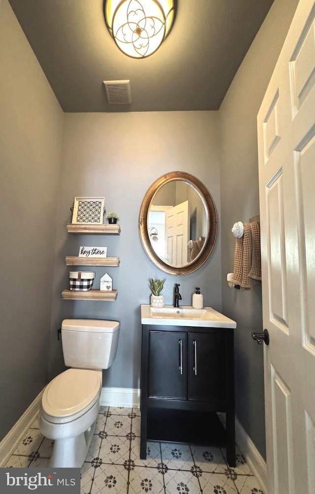 bathroom with vanity, toilet, baseboards, and visible vents