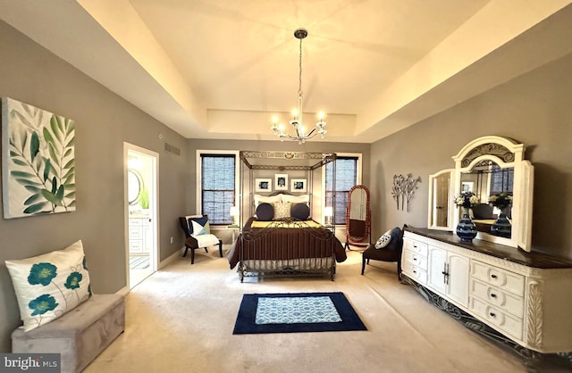 bedroom featuring visible vents, light carpet, ensuite bathroom, an inviting chandelier, and a raised ceiling