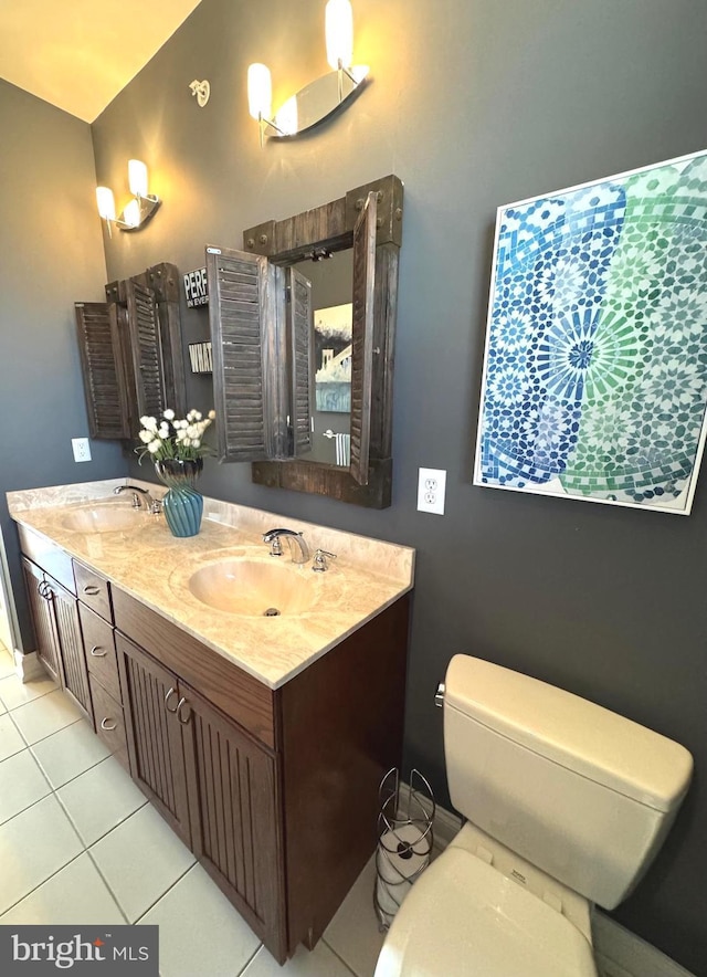 bathroom featuring tile patterned flooring, double vanity, toilet, and a sink