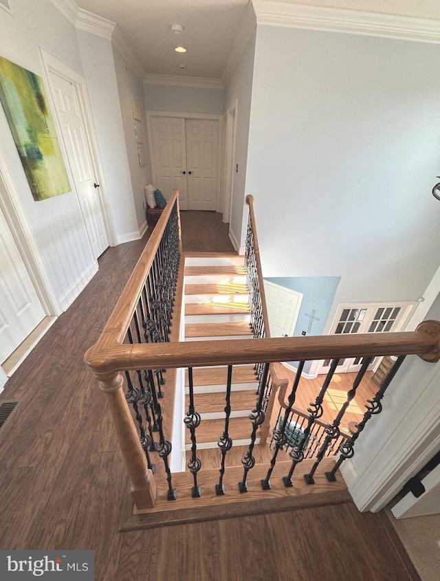 stairway with wood finished floors, baseboards, and ornamental molding