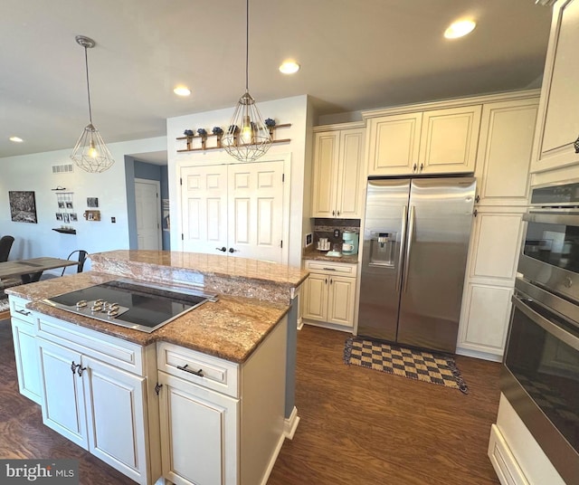 kitchen featuring pendant lighting, cream cabinetry, and appliances with stainless steel finishes