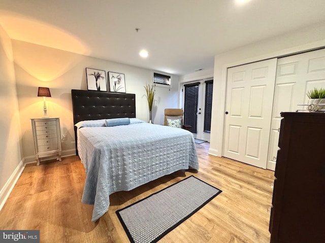 bedroom featuring a closet, baseboards, an AC wall unit, and light wood-style flooring