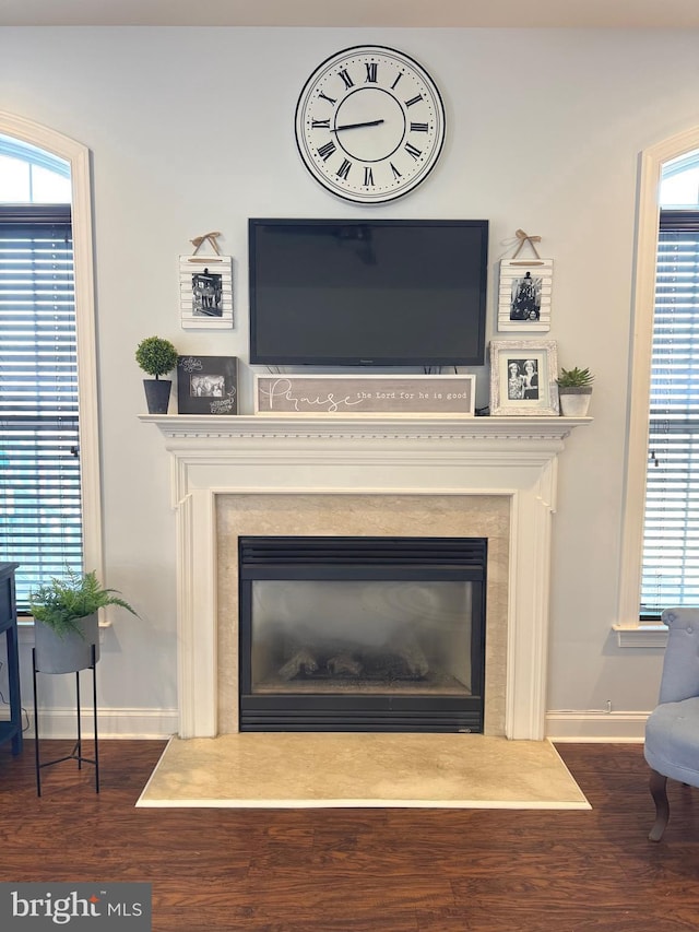 interior details with a glass covered fireplace, baseboards, and wood finished floors