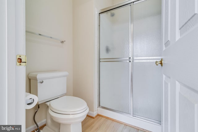 full bathroom featuring a shower stall, toilet, wood finished floors, and baseboards