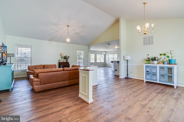 living room featuring a notable chandelier, visible vents, high vaulted ceiling, and wood finished floors