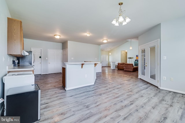 kitchen featuring wood finished floors, baseboards, hanging light fixtures, light countertops, and open floor plan