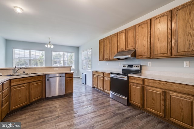 kitchen featuring a sink, brown cabinetry, under cabinet range hood, and stainless steel appliances