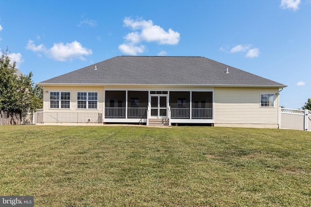 rear view of property with a lawn, a sunroom, roof with shingles, and fence