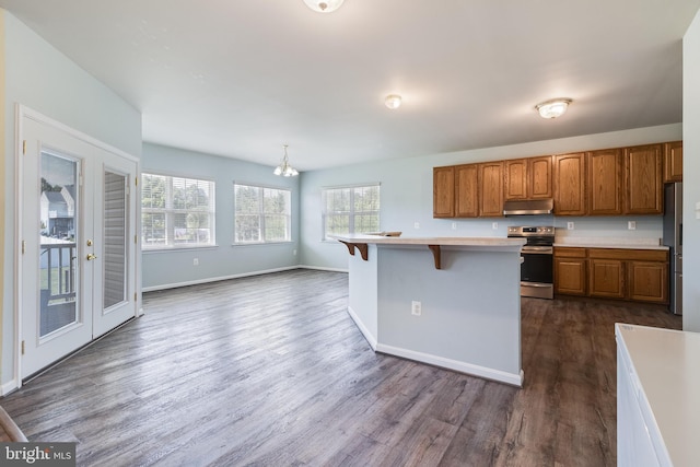 kitchen featuring brown cabinetry, a breakfast bar, stainless steel appliances, light countertops, and under cabinet range hood