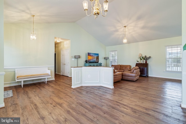 living area featuring a notable chandelier, wood finished floors, baseboards, and high vaulted ceiling