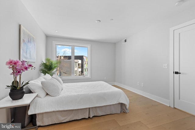 bedroom featuring visible vents, baseboards, and light wood finished floors