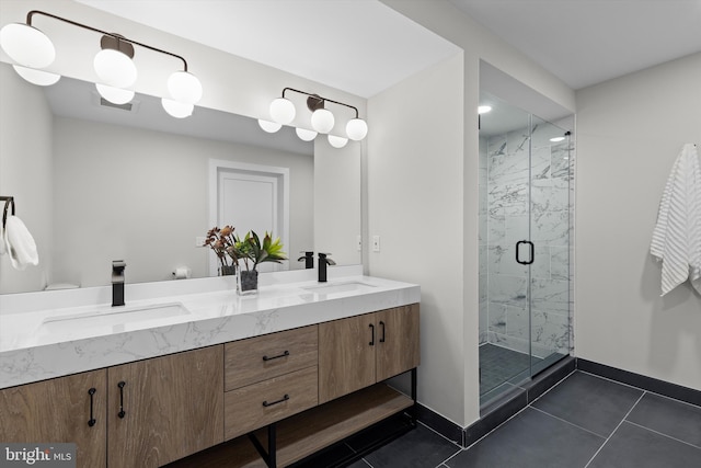 bathroom with double vanity, baseboards, a marble finish shower, and a sink