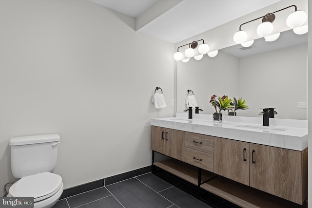 bathroom with tile patterned flooring, baseboards, toilet, double vanity, and a sink