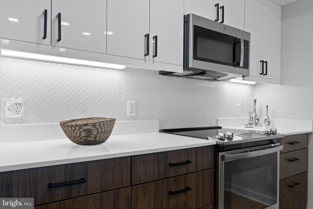 kitchen featuring modern cabinets, decorative backsplash, appliances with stainless steel finishes, and light countertops